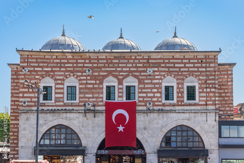 The entrance to the historical Spice Bazaar in Eminönü. Brick, stone architectural example domed structure. It is frequented by tourists. The most heavily used grand bazaar entrance. photo