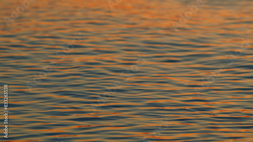 Surface Water Of Sea Or Ocean At Sunset Time With Golden Light. Rippled Surface Of Orange And Teal Tones Sea Water In Sunset. Slow motion. © artifex.orlova