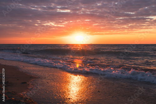 The sun is setting over the ocean  waves crashing on the beach