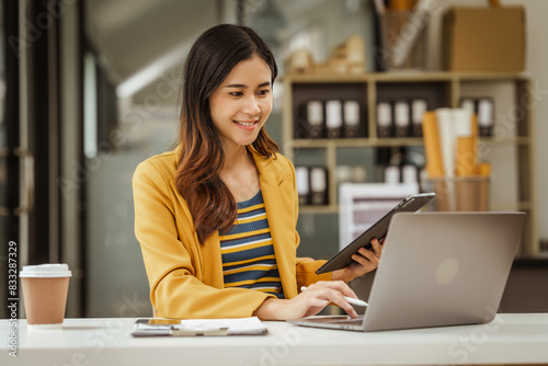 A young woman and other Asian individuals in formal suits are seen working at desks with laptops, portraying a successful and happy demeanor.