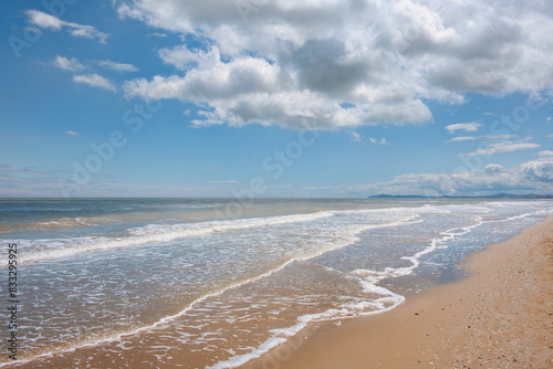 Fototapeta Naklejka Na Ścianę i Meble -  Waves breaking over the sandy shores of the wild beach along the Adriatic sea in Rimini, Italy, European seasonal travel destination popular for leisure activities, water sports and coastal scenery