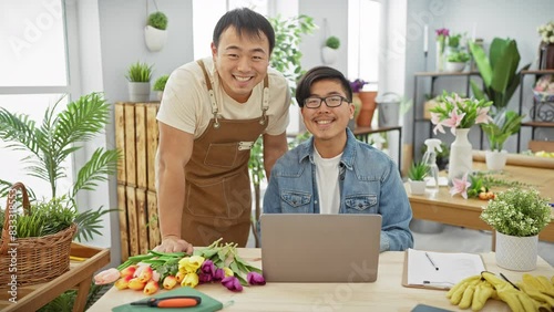 Two men working together in a flower shop, with fresh tulips, plants, and a laptop on their desk, suggest a professional yet congenial business setting.