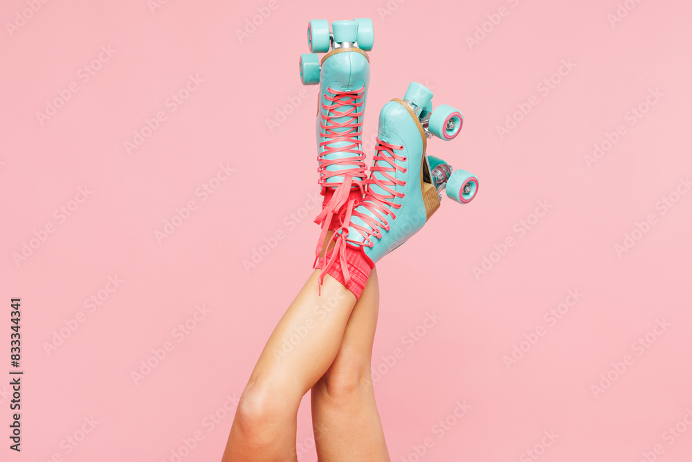 Close up cropped young woman she wearing modern blue rollers rollerblading raise up legs isolated on plain pastel light pink color wall background. Summer season hobby sport lifestyle leisure concept. Close up cropped young woman she wearing modern blue rollers rollerblading raise up legs isolated on plain pastel light pink color wall background. Summer season hobby sport lifestyle leisure concept.