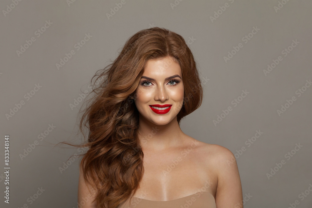 Stylish fashionable redhead woman with long wavy hair and make-up. Studio headshot portrait of fashion model lady with red colorful shine lipstick. Haircare, skin care and coloration concept