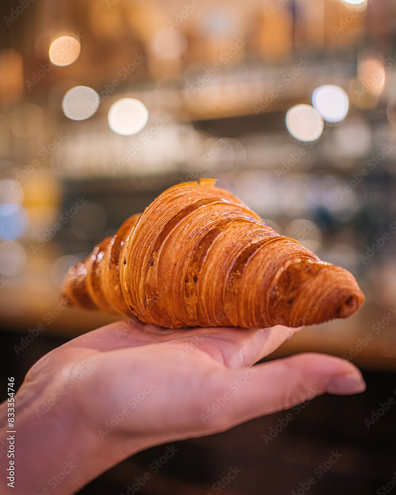 Obraz premium Hand Presenting a Perfectly Baked Croissant