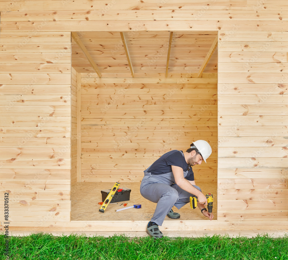 Construction man, builder man construct new wooden home, tiny house style. Spirit level, screw, tool bag and charged drill. Wood shelter style. Construction man, builder man construct new wooden home, tiny house style. Spirit level, screw, tool bag and charged drill. Wood shelter style.
