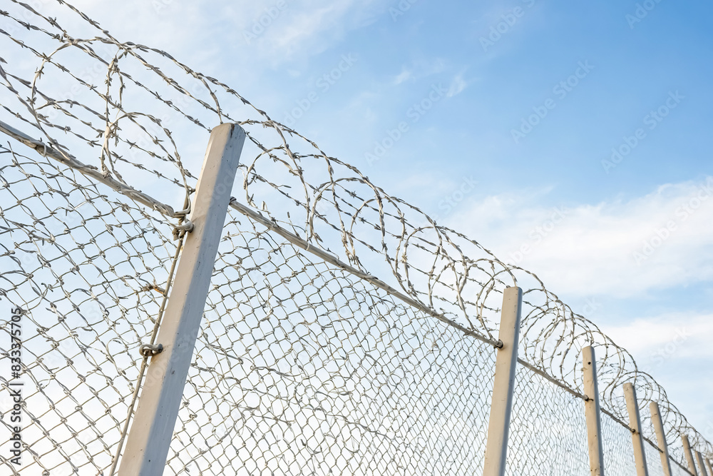 Barbed wire fence against blue sky