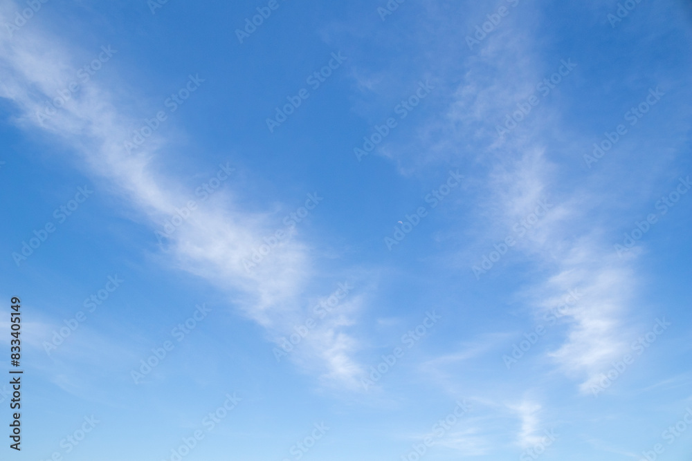 Obraz premium Diagonal lines of cloud surrounding a small moon against a blue sky