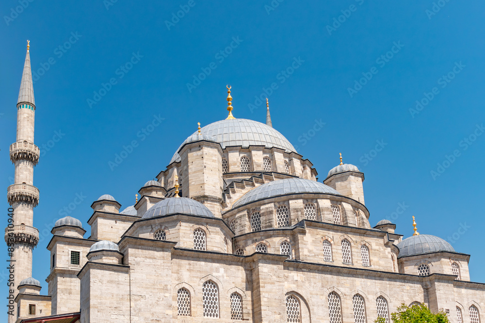 View of the dome and minarets with a blue isolated sky from outside the New Mosque in Eminönü, Istanbul.