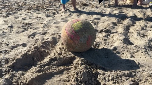 Left-handed person with his bare foot hits a beach soccer ball in the sand. Conceotp of vacation, fun, summer, sport and hitting.