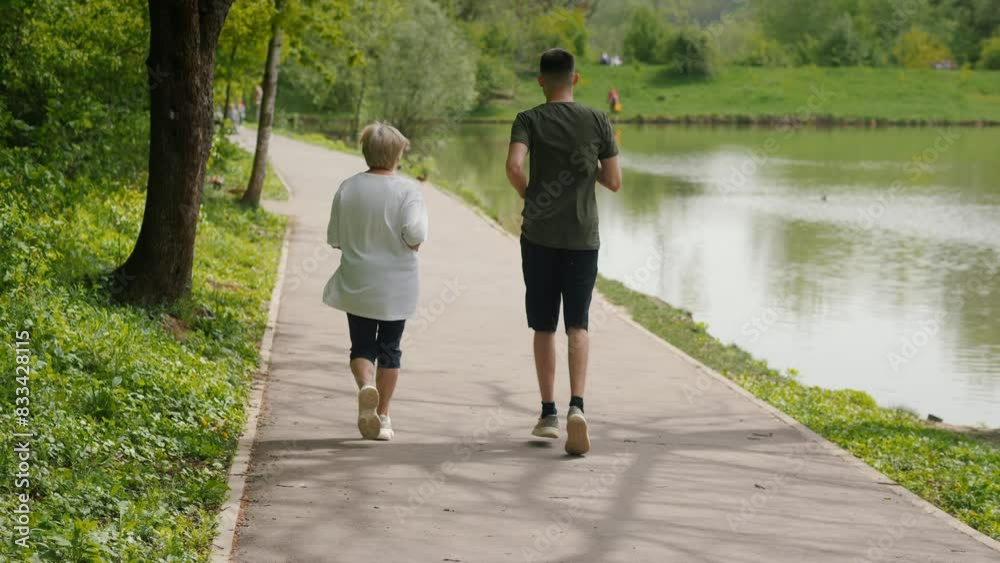 Middle-aged woman and young man jogging by a pond in a park. Middle-aged woman and young man jogging by a pond in a park.