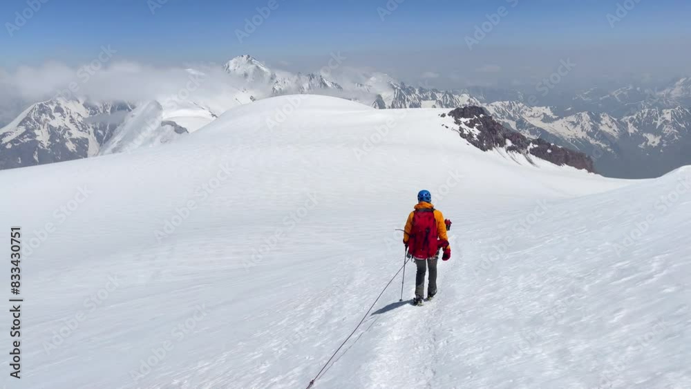 Descending from Kazbek (Kazbegi) summit 5054m rope team dressed mountaineering clothes, boots with crampons ascending by snowy slope with blue sky background and bright sun. Caucasus mountains. 4K Descending from Kazbek (Kazbegi) summit 5054m rope team dressed mountaineering clothes, boots with crampons ascending by snowy slope with blue sky background and bright sun. Caucasus mountains. 4K