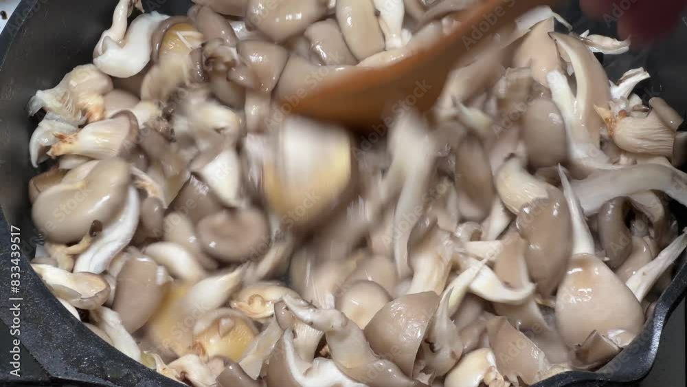 Stirring with a spatula of oyster mushrooms in frying pan