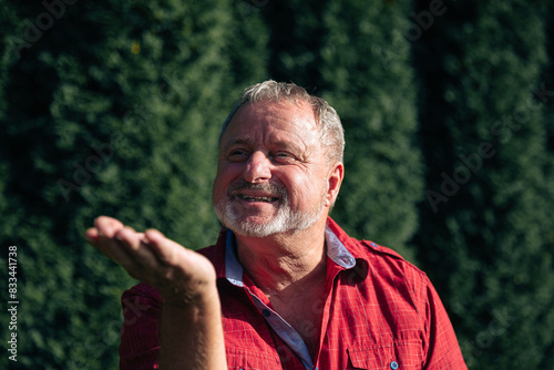 oyful Senior Man in Red Shirt Enjoying a Sunny Day in the Garden photo