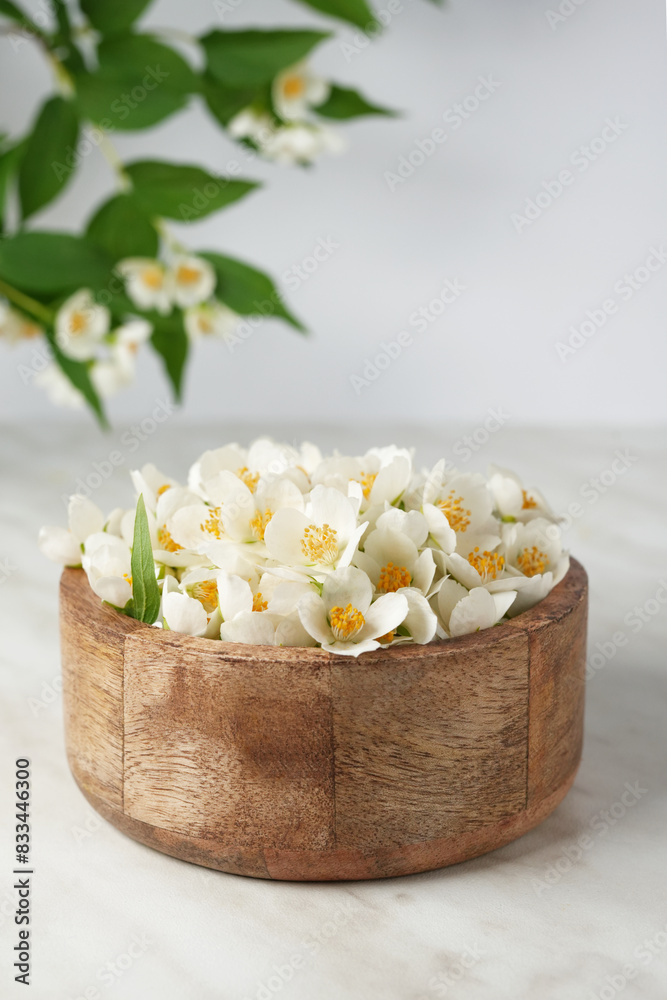 Fresh jasmine flowers in wodden bowl on white marble background. Side view. Fresh jasmine flowers in wodden bowl on white marble background. Side view.