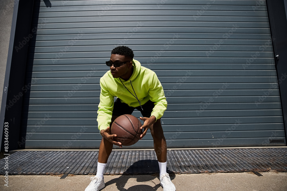 Fototapeta premium Handsome man in yellow hoodie with basketball.