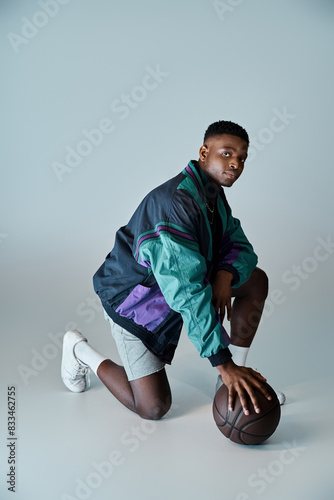Fotografie Stylish young man crouching with basketball ball.