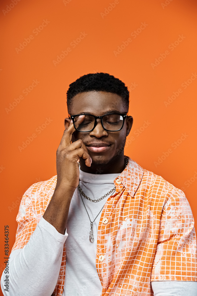 A fashionable young African American man wearing glasses and an orange shirt. A fashionable young African American man wearing glasses and an orange shirt.