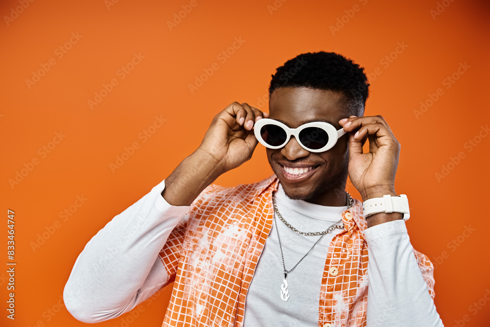 Young man in sunglasses on vibrant orange backdrop. Young man in sunglasses on vibrant orange backdrop.