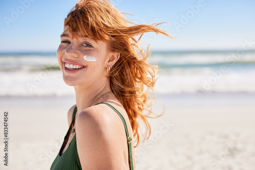Smiling young woman sunbathing with sunscreen on cheek