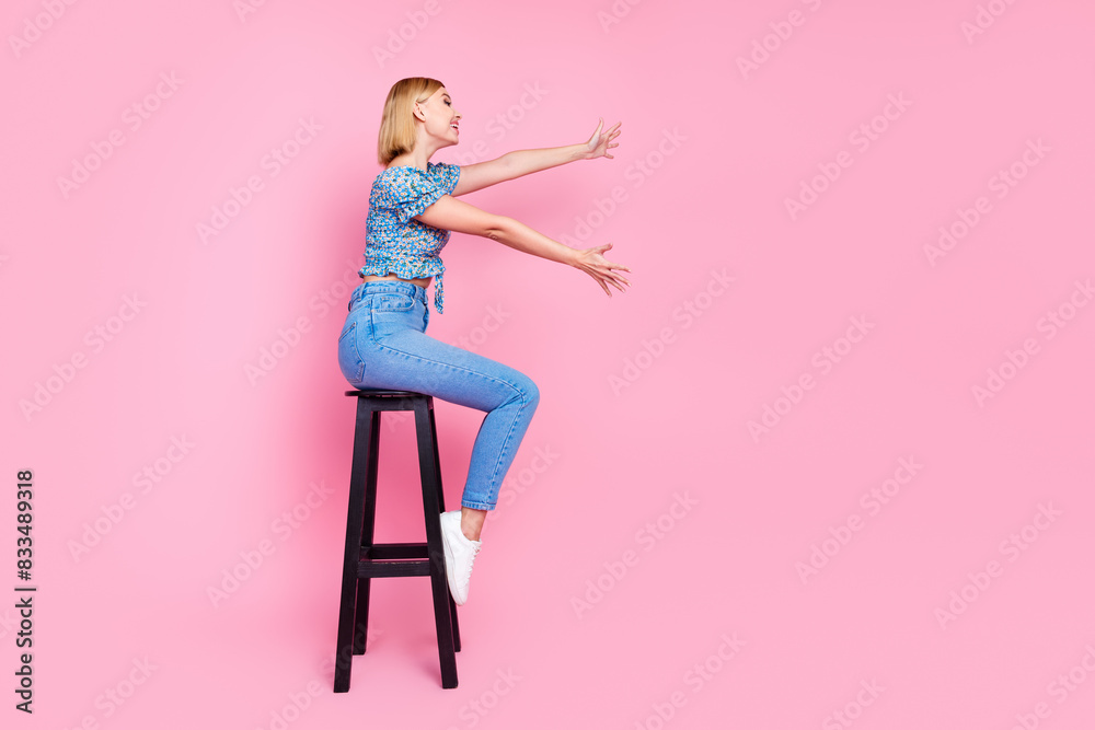 Full length photo of shiny attractive lady dressed blue top sitting bar chair holding empty space isolated pink color background Full length photo of shiny attractive lady dressed blue top sitting bar chair holding empty space isolated pink color background