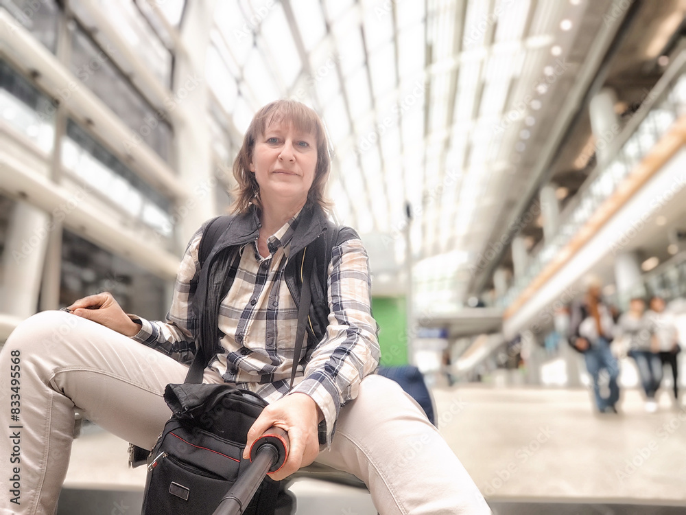 Middle-Aged Woman Taking Selfie at Airport Before Departure. A middle-aged woman captures a selfie in an airy airport terminal