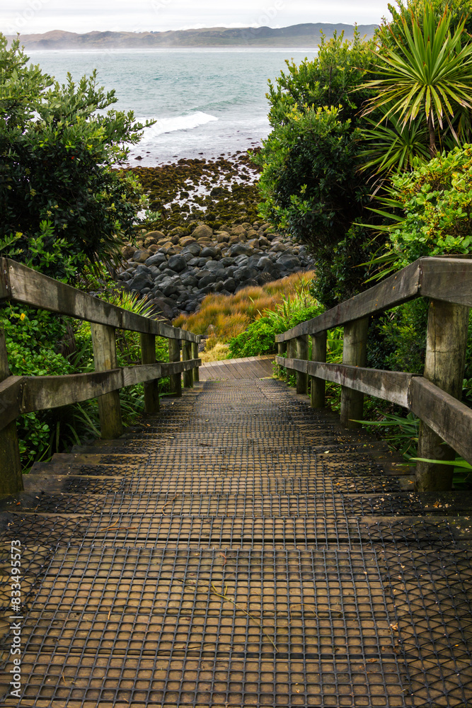 Coastal path with wooden steps down to the rocky coastline. Manu Bay, Raglan, North Island, New Zealand