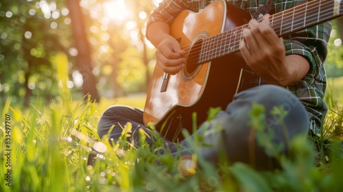 Young man playing the guitar on grass, capturing a relaxed outdoor atmosphere. Perfect for themes of music and nature photo