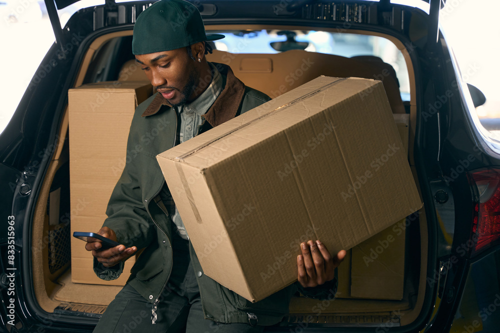 Man came out with a box in his hand in front of the open trunk of the car Man came out with a box in his hand in front of the open trunk of the car