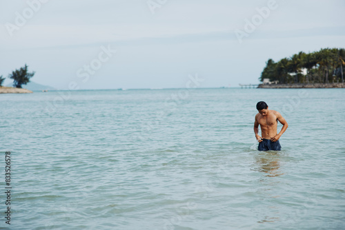 Smiling Asian Man Enjoying a Refreshing Swim in the Tropical Ocean, Embracing the Freedom and Joy of a Beach Vacation