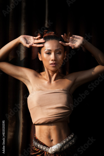 Portrait of an Asian woman in traditional Thai clothing with natural light on an old rust-colored background.