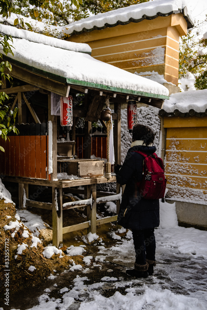 a woman walks into a snowy building to look at an open air shrine a woman walks into a snowy building to look at an open air shrine