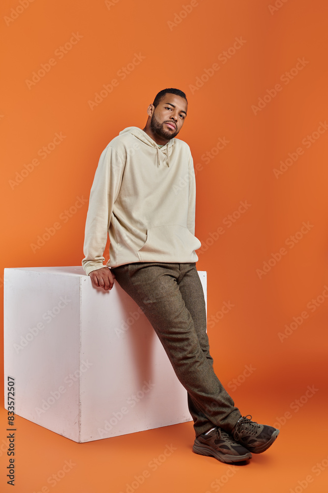 Stylish African American man posing on white box against vibrant background. Stylish African American man posing on white box against vibrant background.