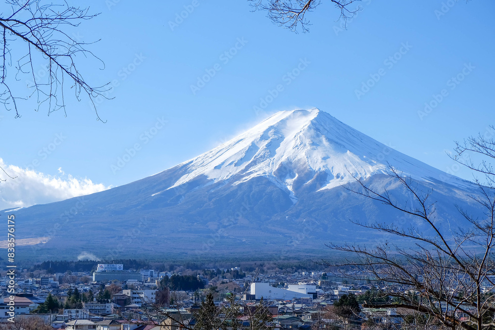 Fototapeta premium A distant view on Mt Fuji in Japan on a clear,The top parts of the volcano are covered with a layer of snow.