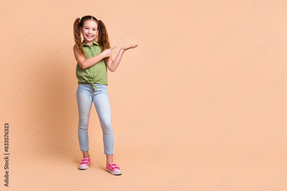 Photo of positive kid girl hold hand empty space demonstrate with index finger isolated pastel color background Photo of positive kid girl hold hand empty space demonstrate with index finger isolated pastel color background