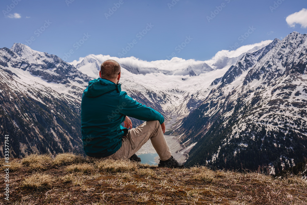 Perched atop the rugged peaks, a solitary man stands, the vast expanse of the mountains stretching out beneath him. Perched atop the rugged peaks, a solitary man stands, the vast expanse of the mountains stretching out beneath him.
