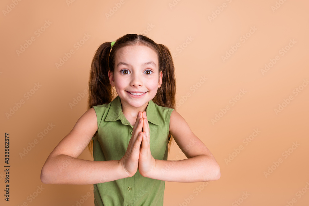 Photo of positive funny kid girl hands together pleading isolated over pastel color background
