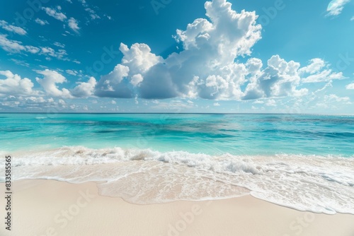 A beautiful beach with a blue ocean and white clouds in the sky