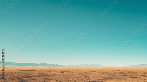 A vast desert landscape with golden sand dunes stretching towards a clear blue sky