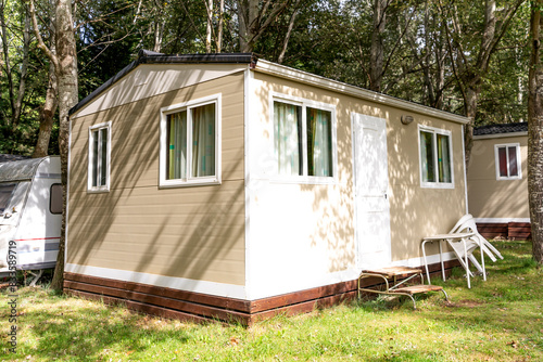 Prefabricated mobile modular container house in forest camping with porch. Temporary house in nature, forest rest
