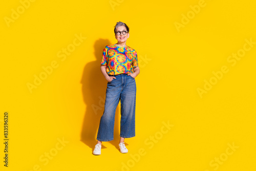 Photo of lovely retired woman wear trendy print clothes empty space isolated on vivid yellow color background