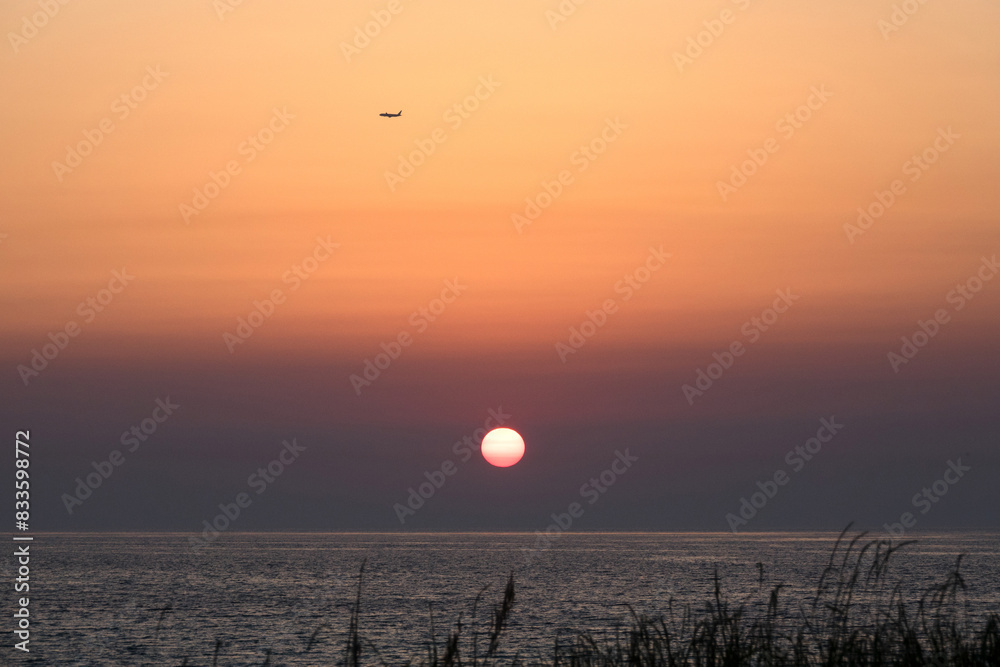 View of the sunset with the flying airplane