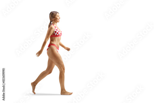 Full length profile shot of a young attractive woman in bikini walking