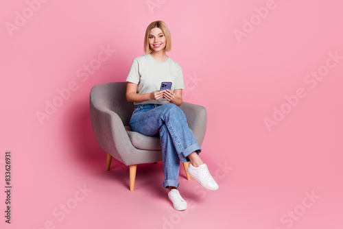 Photo of lovely adorable girl wear trendy clothes sitting soft chair use apple iphone isolated on pink color background