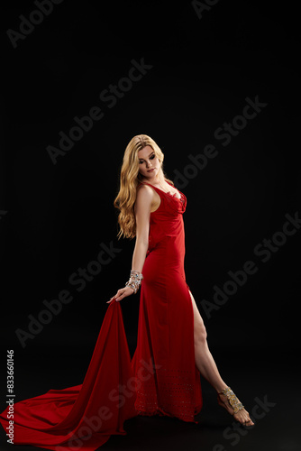 A graceful woman in a vibrant red dress strikes a pose.