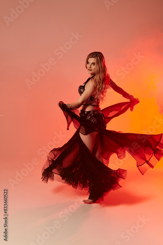 A captivating young woman in a black dress gracefully dancing.