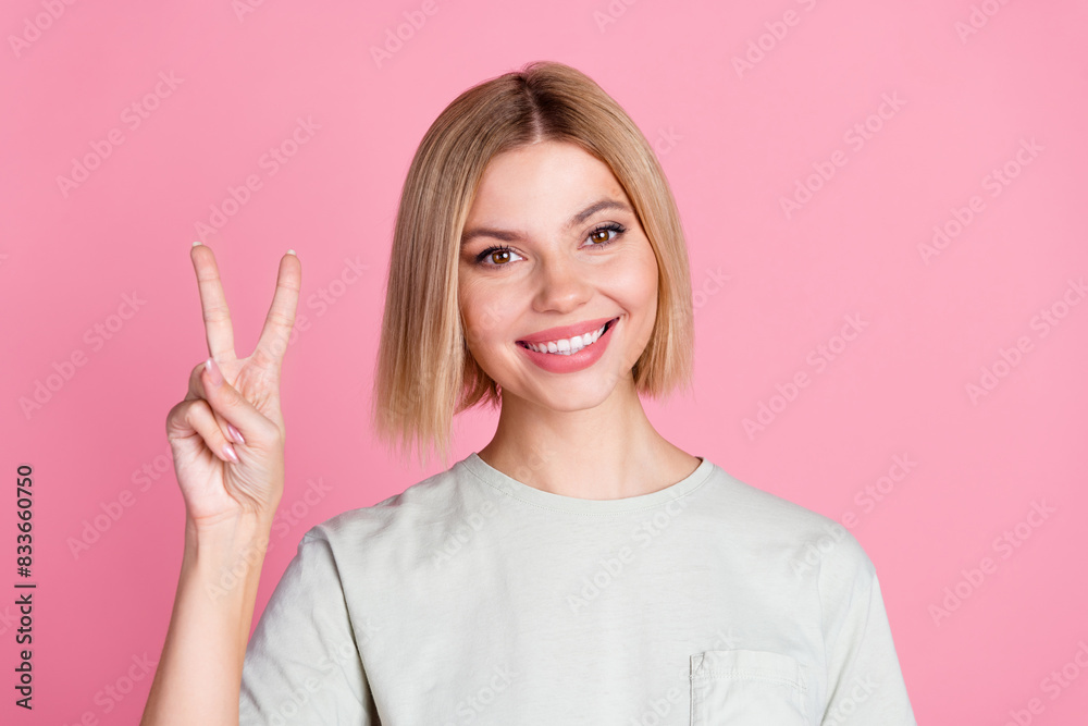 Portrait of toothy beaming nice girl with bob hairstyle wear white t-shirt showing v-sign symbol isolated on pink color background Portrait of toothy beaming nice girl with bob hairstyle wear white t-shirt showing v-sign symbol isolated on pink color background