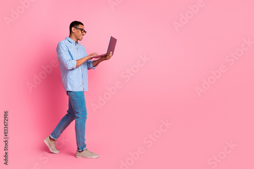 Full length photo of handsome confident guy wear plaid shirt texting modern gadget emtpy space isolated pink color background