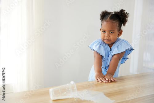 Slika na platnu little African girl spilling milk and feeling sad on the table