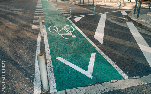 A dedicated green bike lane marked with white bike symbol and directional arrow, separated from the main road by white dashed lines and poles, promoting safe cycling in urban areas